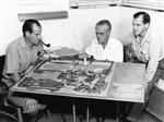 black and white image of three men looking over miniature model of Palm Springs High School 